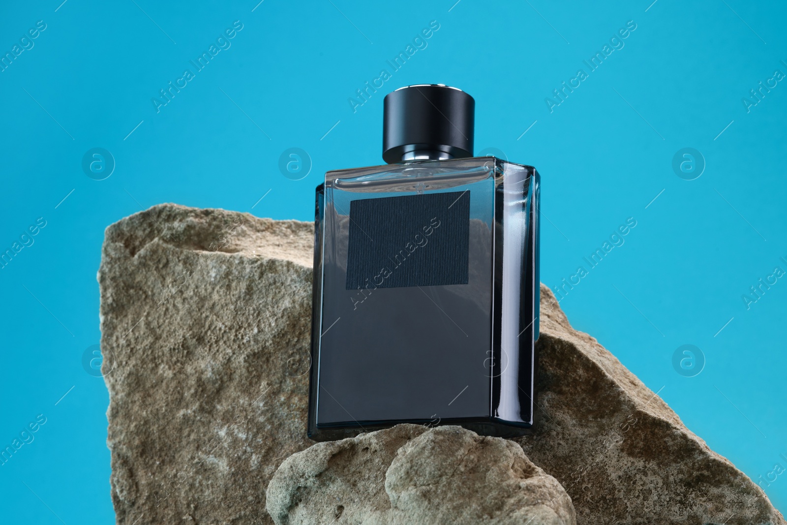 Photo of Stylish presentation of luxury men`s perfume on stones against light blue background