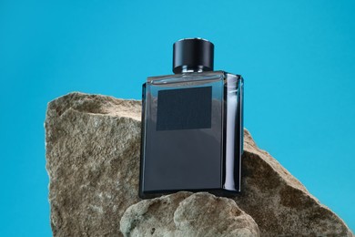 Stylish presentation of luxury men`s perfume on stones against light blue background