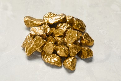 Pile of gold nuggets on light grey marble table, above view