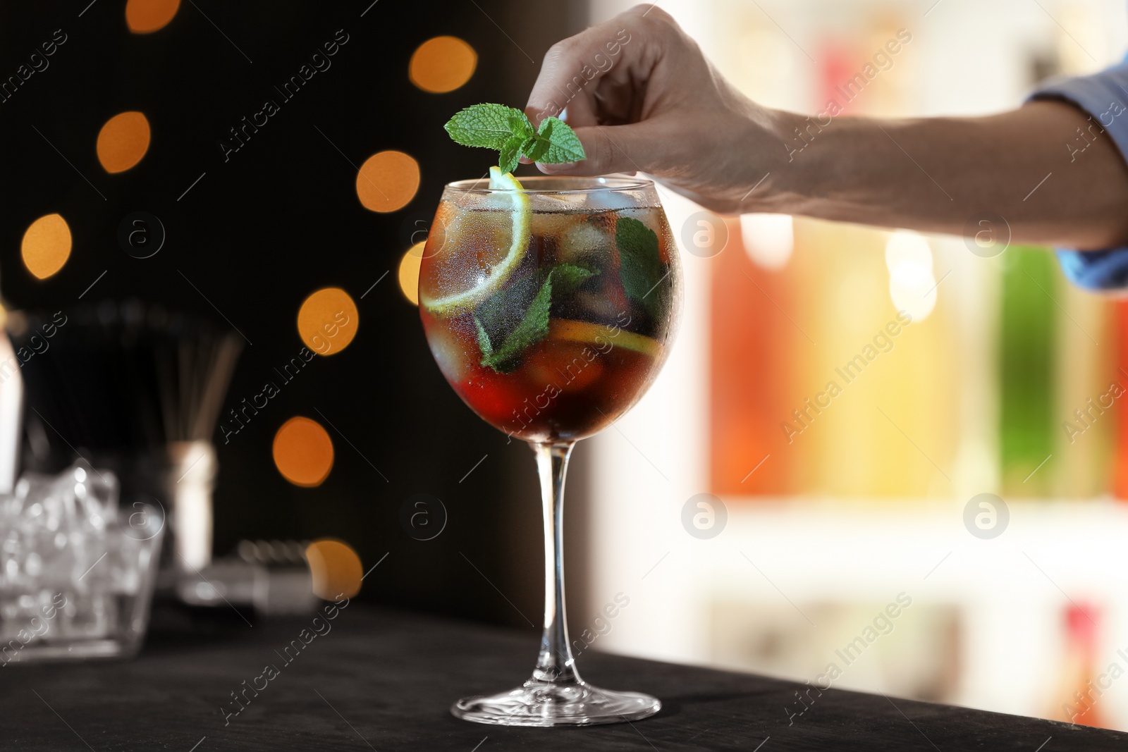 Photo of Woman preparing fresh alcoholic cocktail with lemon and mint at bar counter, closeup