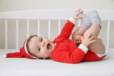 Cute baby wearing festive Christmas costume lying in crib
