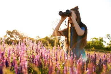 Teenage girl with binoculars in field. Summer camp