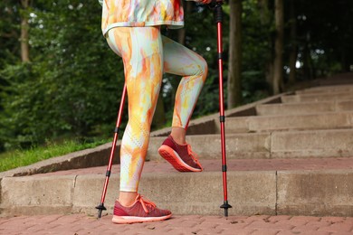 Young woman practicing Nordic walking with poles on steps outdoors, closeup