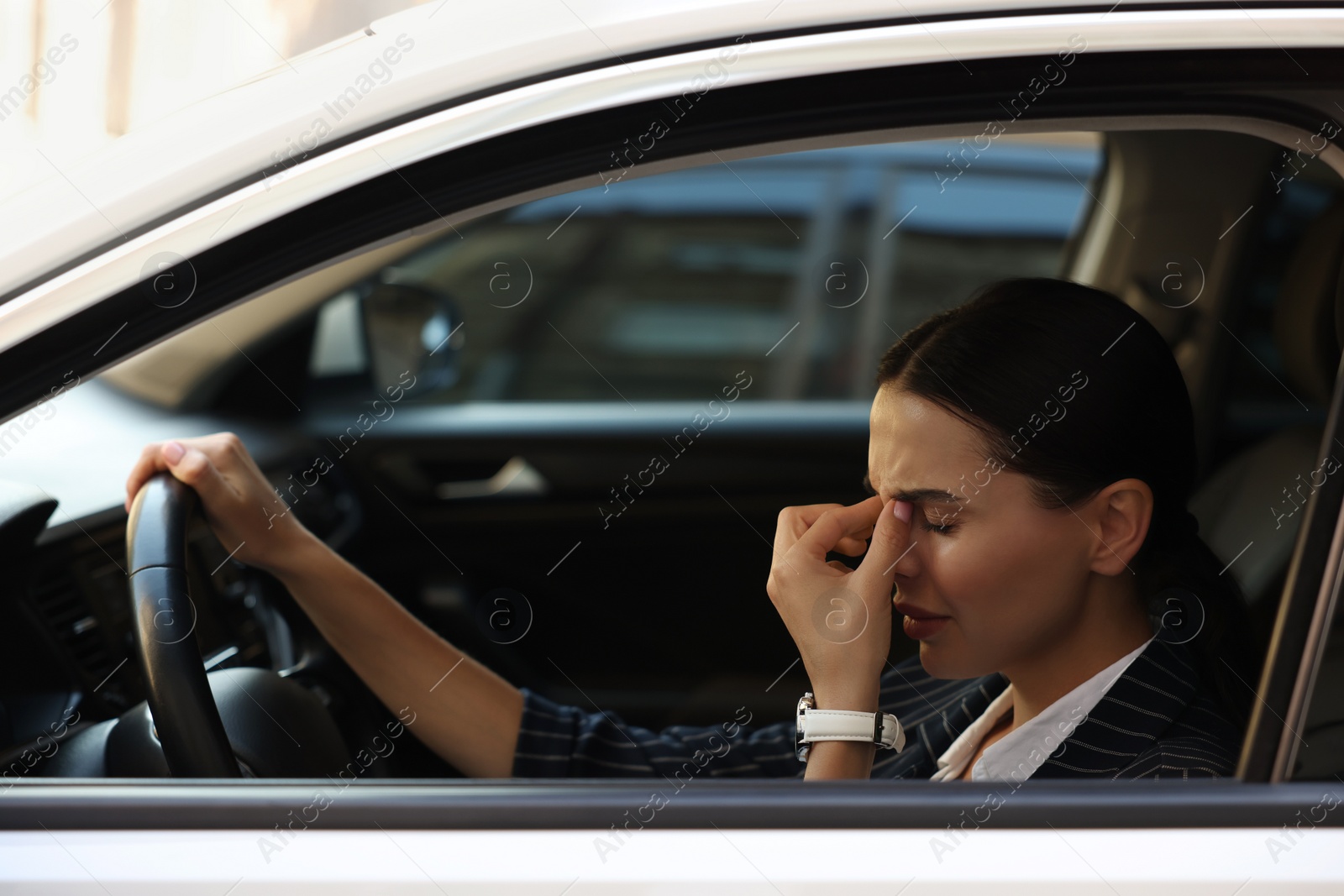 Photo of Tired driver in her car, view from outside. Stuck in traffic jam