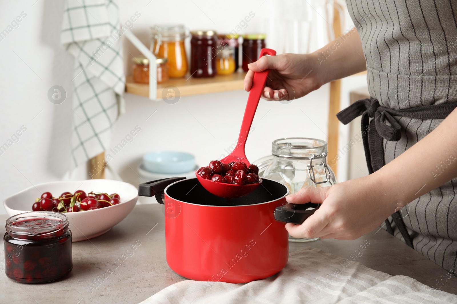 Photo of Woman making pickled cherries at table indoors, closeup