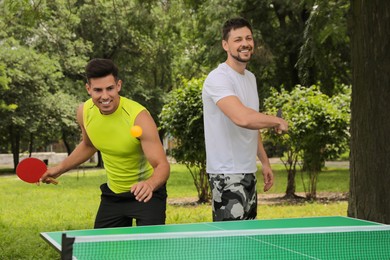 Photo of Men playing ping pong in park on summer day
