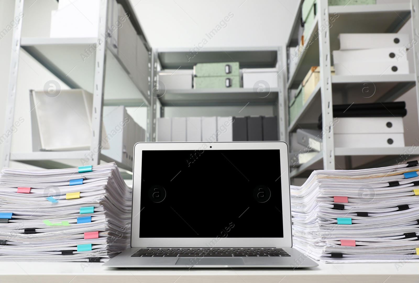 Photo of Laptop and documents on desk in office. Space for text