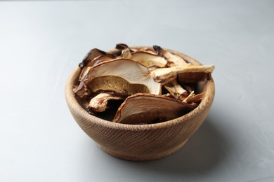 Bowl of dried mushrooms on color background