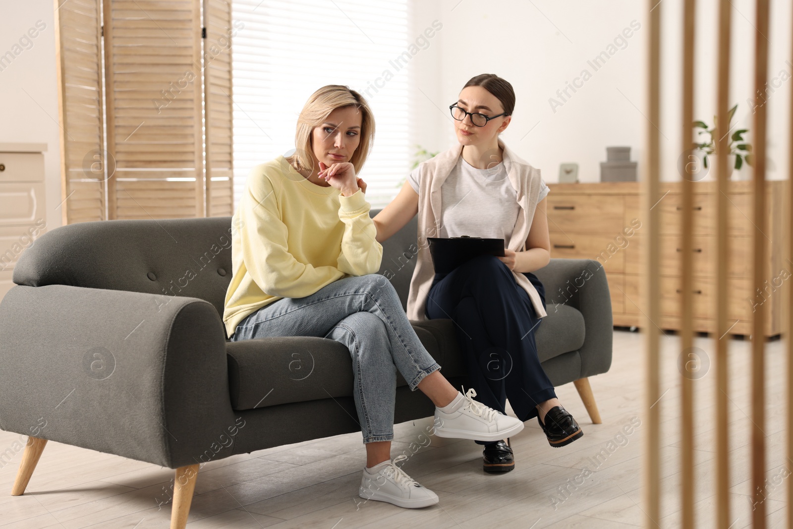 Photo of Professional psychotherapist working with on sofa patient in office