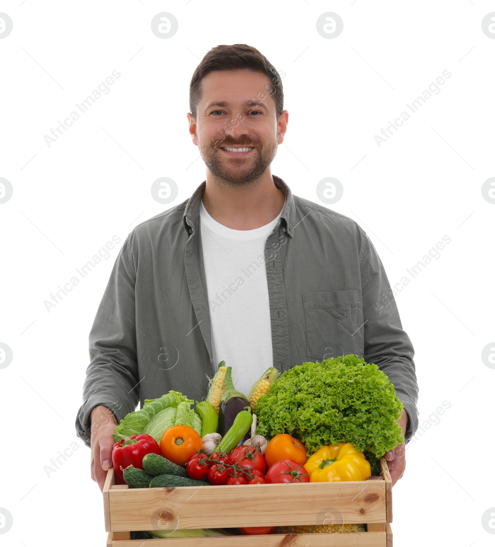 Photo of Harvesting season. Happy farmer holding wooden crate with vegetables on white background