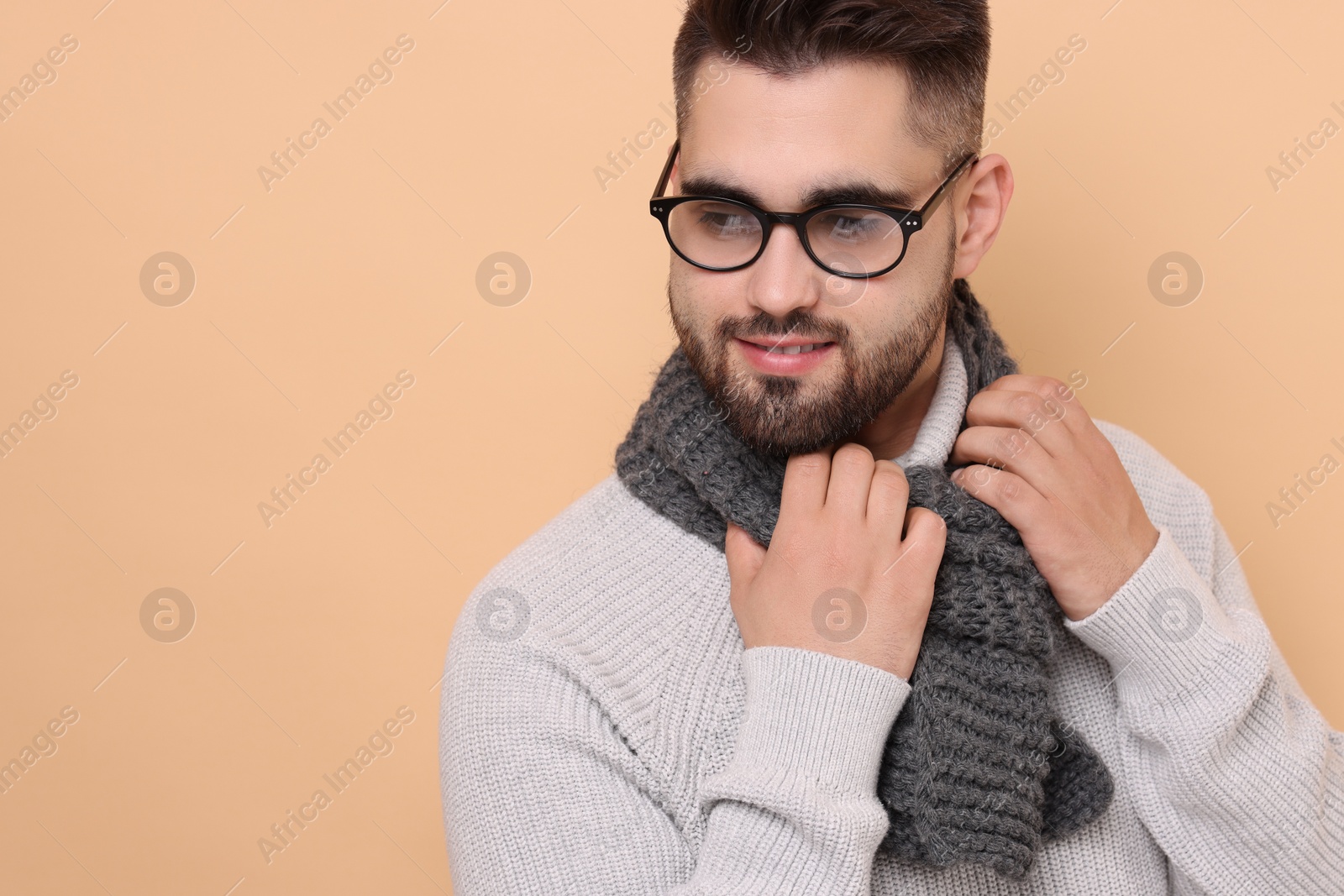Photo of Handsome man in knitted scarf on beige background. Space for text