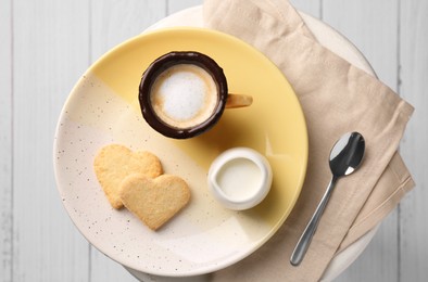 Photo of Delicious edible biscuit cup with coffee, milk and heart shaped cookies on white table, flat lay