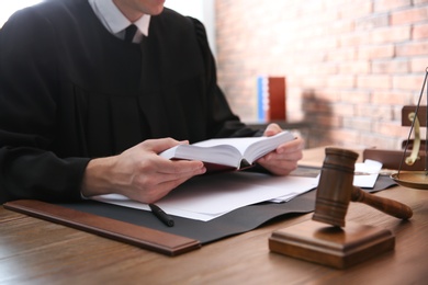 Photo of Judge working at table in office, closeup. Law and justice concept