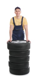 Male mechanic with car tires on white background