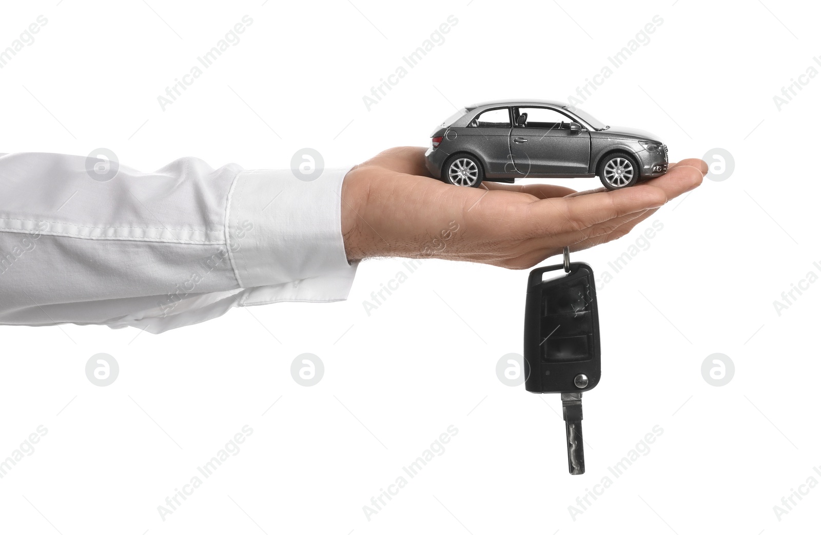 Photo of Man holding key and miniature automobile model on white background, closeup. Car buying