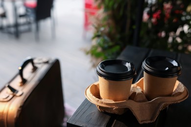 Photo of Paper coffee cups on wooden table in outdoor cafe.