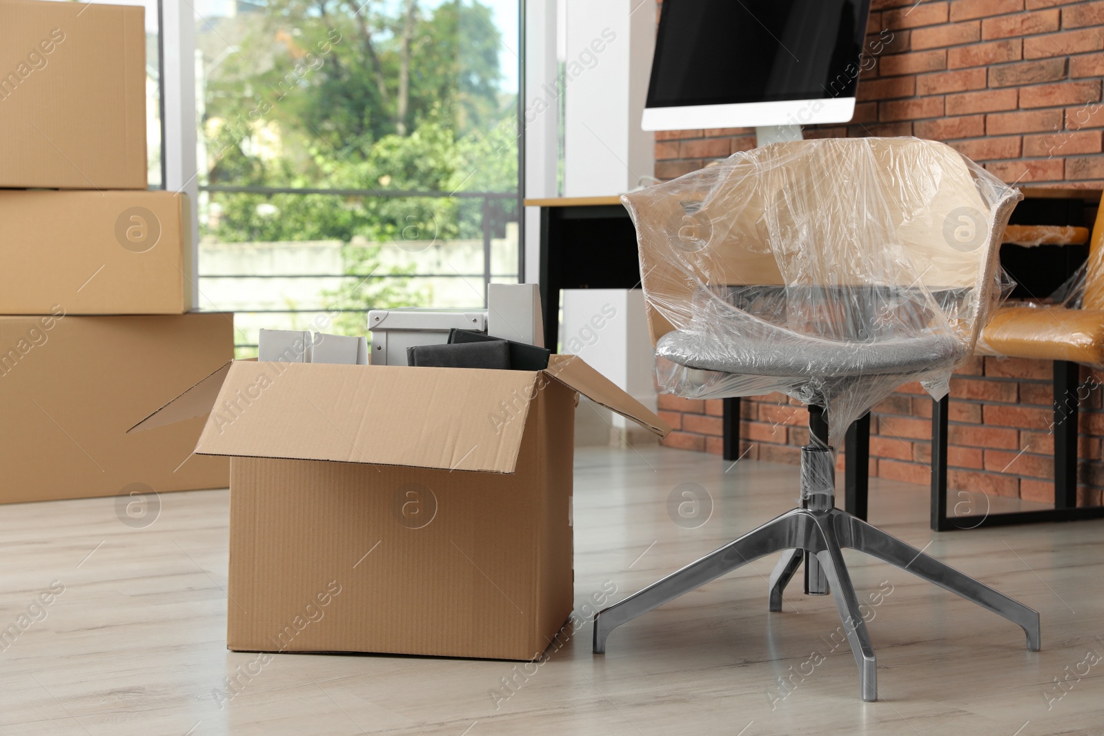 Photo of Cardboard box with belongings and packed chair in office. Moving service