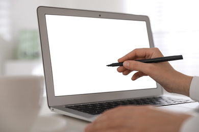 Photo of Woman pointing at modern laptop with blank screen, closeup