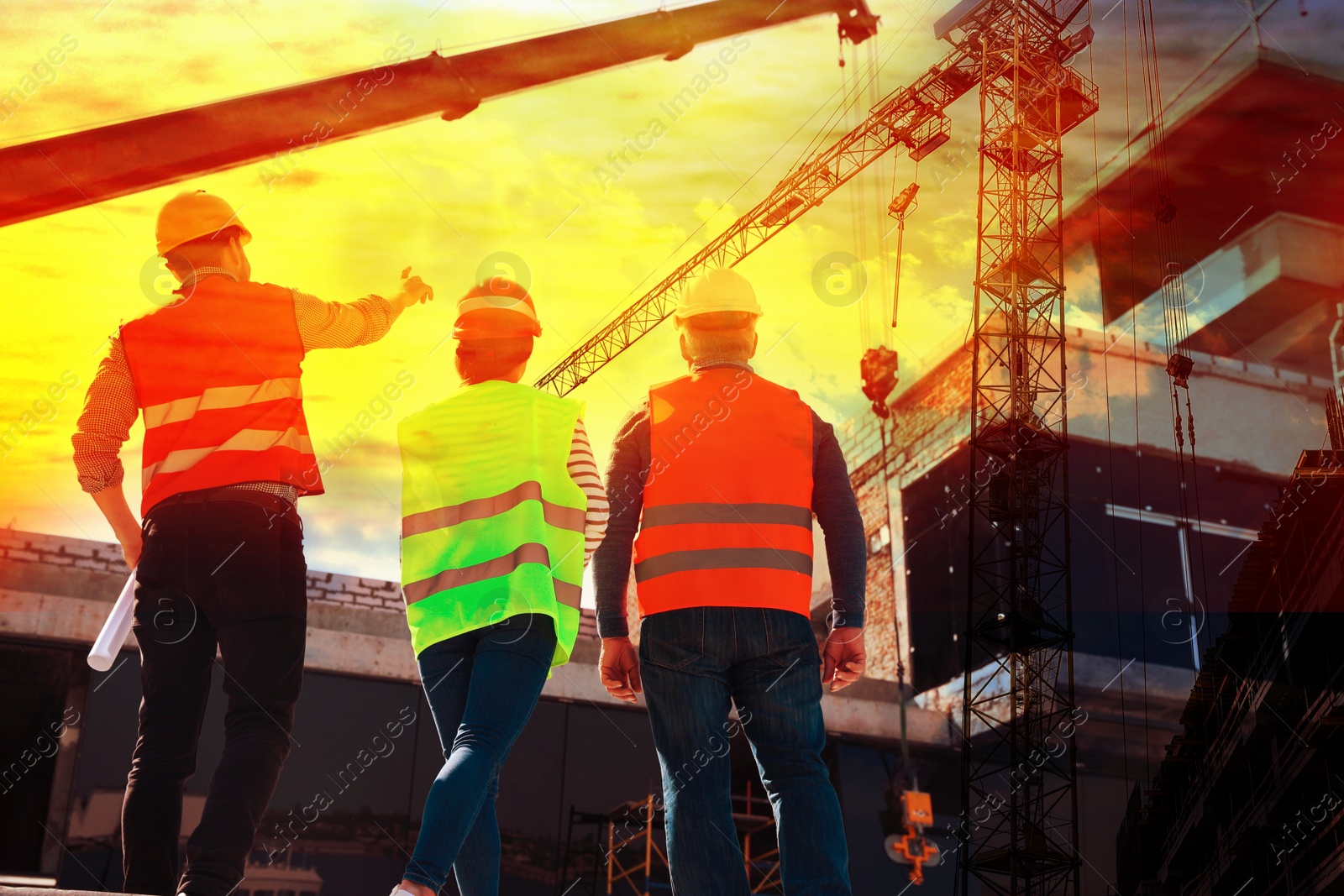 Image of Professional engineers in safety equipment at construction site, back view