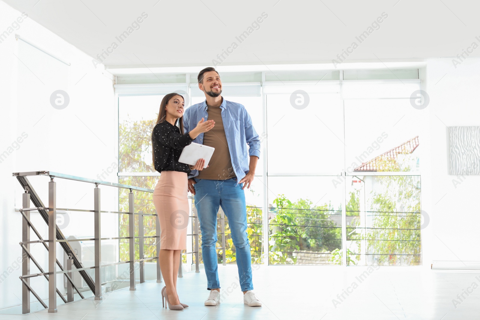 Photo of Female real estate agent showing new house to man, indoors