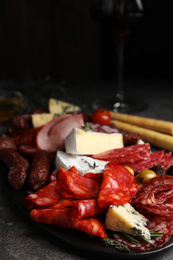 Photo of Tasty salami with other delicacies served on grey table