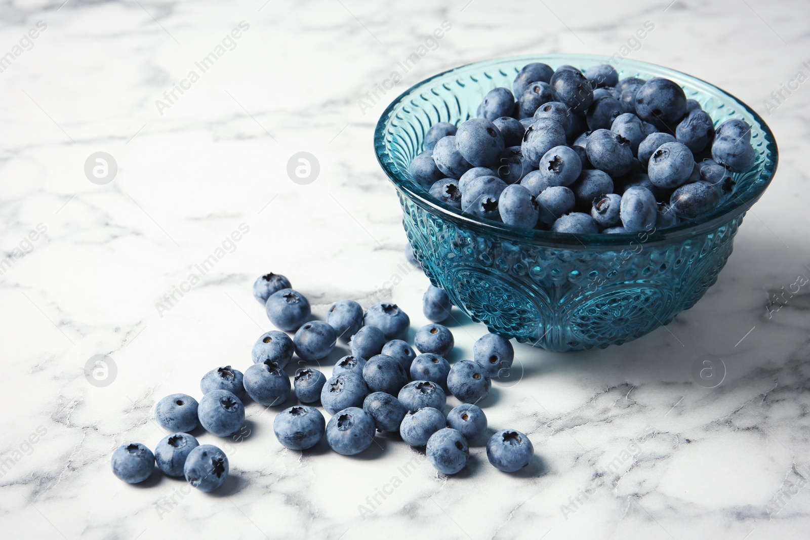 Photo of Bowl with fresh blueberries and space for text on marble table