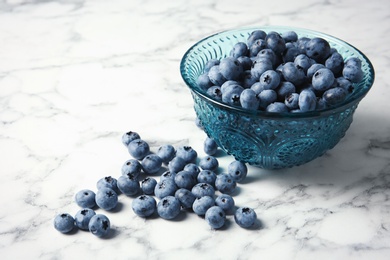 Photo of Bowl with fresh blueberries and space for text on marble table