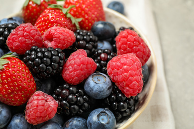 Mix of different fresh berries in bowl on table, closeup