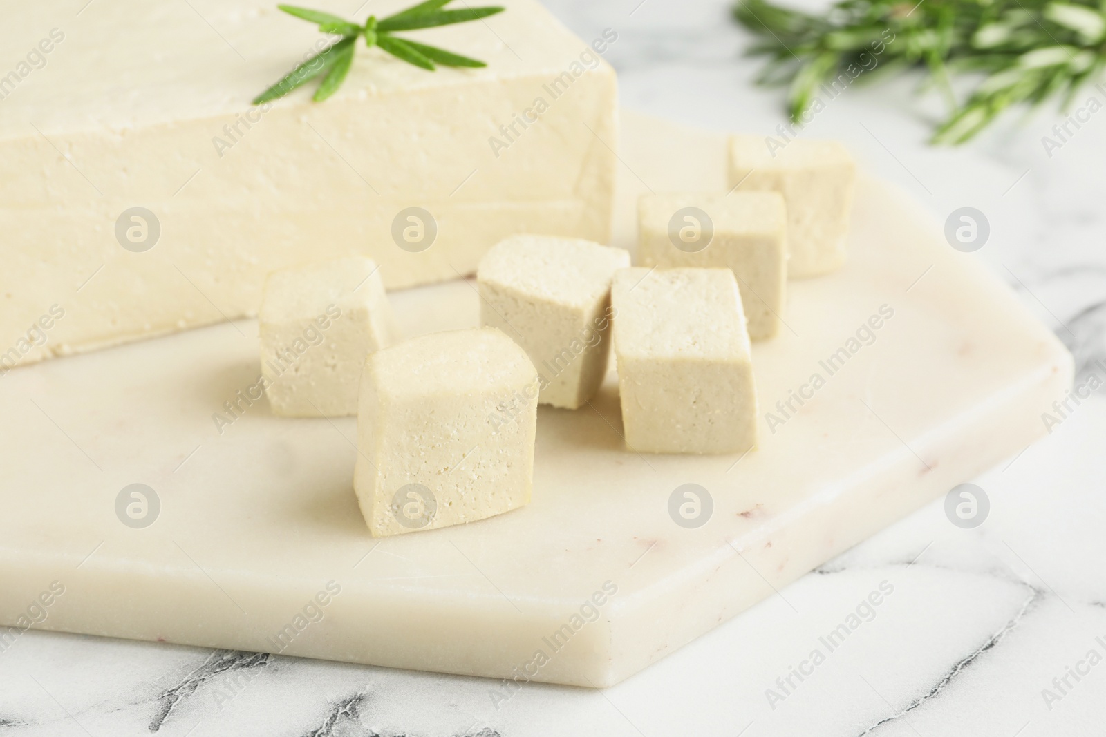 Photo of Delicious tofu with rosemary on white marble table, closeup