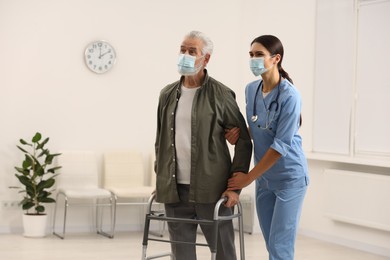 Young nurse supporting elderly patient in hospital, space for text