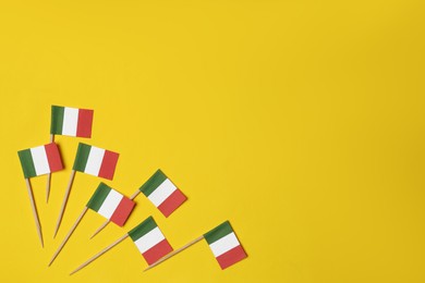 Photo of Small paper flags of Italy on yellow background, flat lay. Space for text
