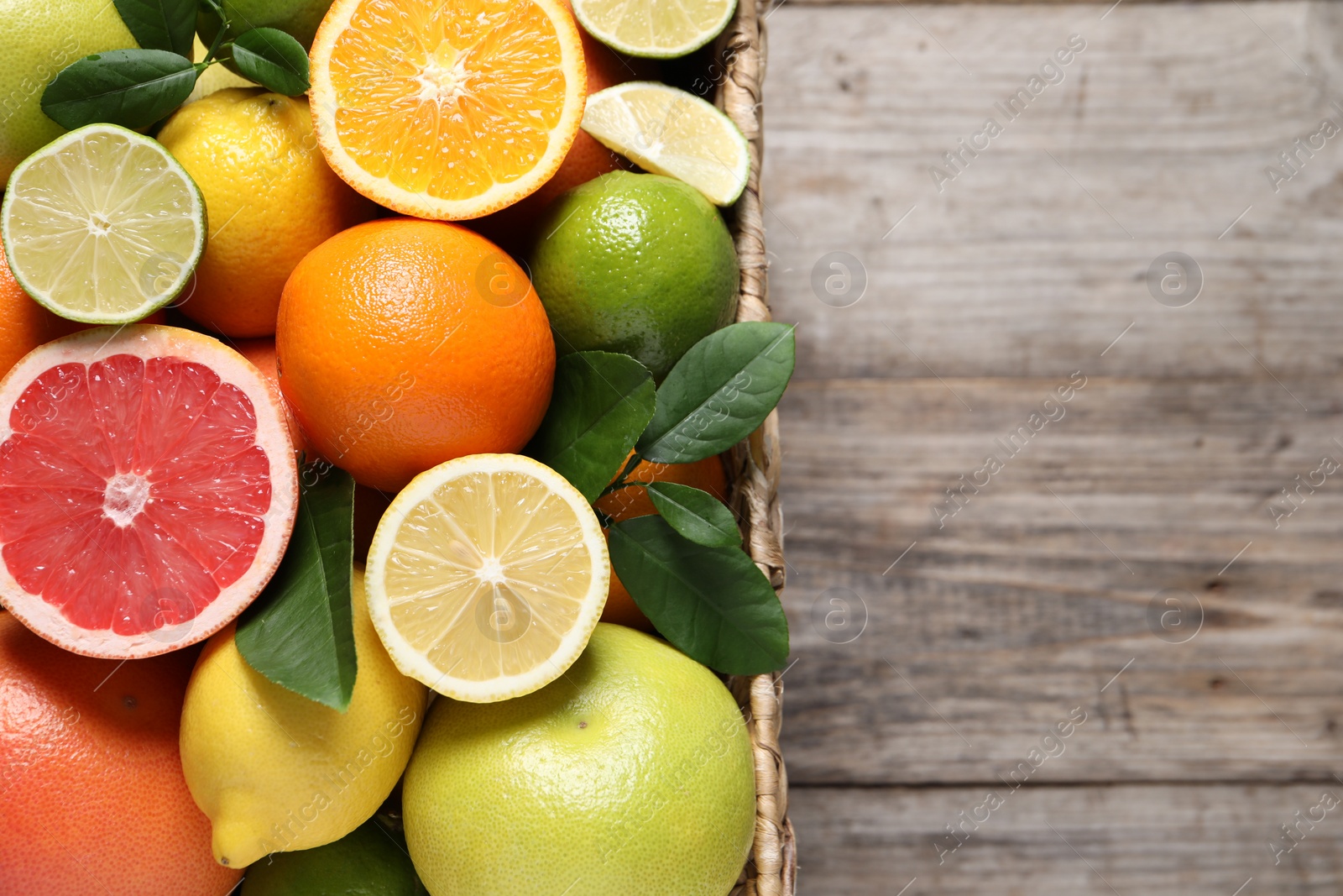 Photo of Different cut and whole citrus fruits on wooden table, top view. Space for text