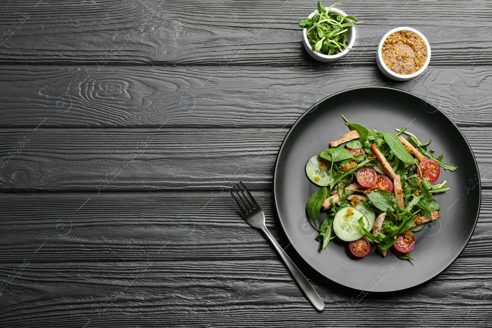 Photo of Delicious fresh chicken salad served on black wooden table, flat lay. Space for text