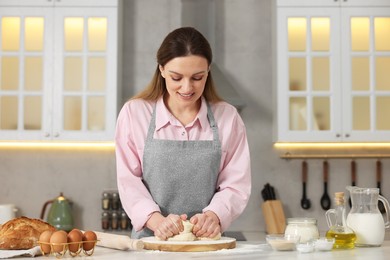 Making bread. Woman kneading dough at white table in kitchen