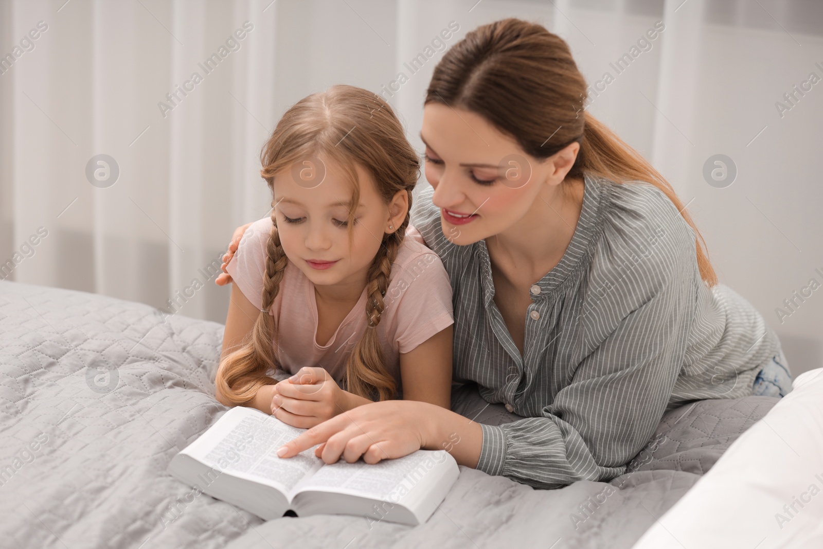 Photo of Girl and her godparent reading Bible together at home