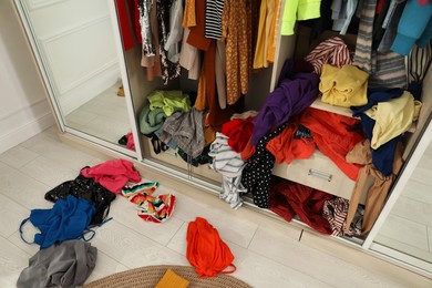 Photo of Messy wardrobe with different clothes indoors. Fast fashion concept