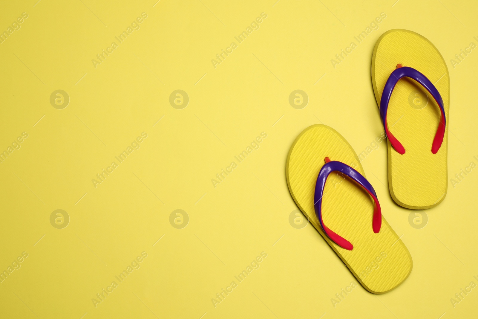 Photo of Flip flops on yellow background, top view with space for text. Beach objects