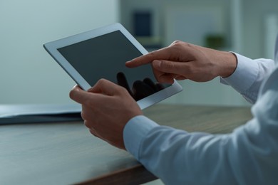 Photo of Man using tablet at wooden table in office, closeup