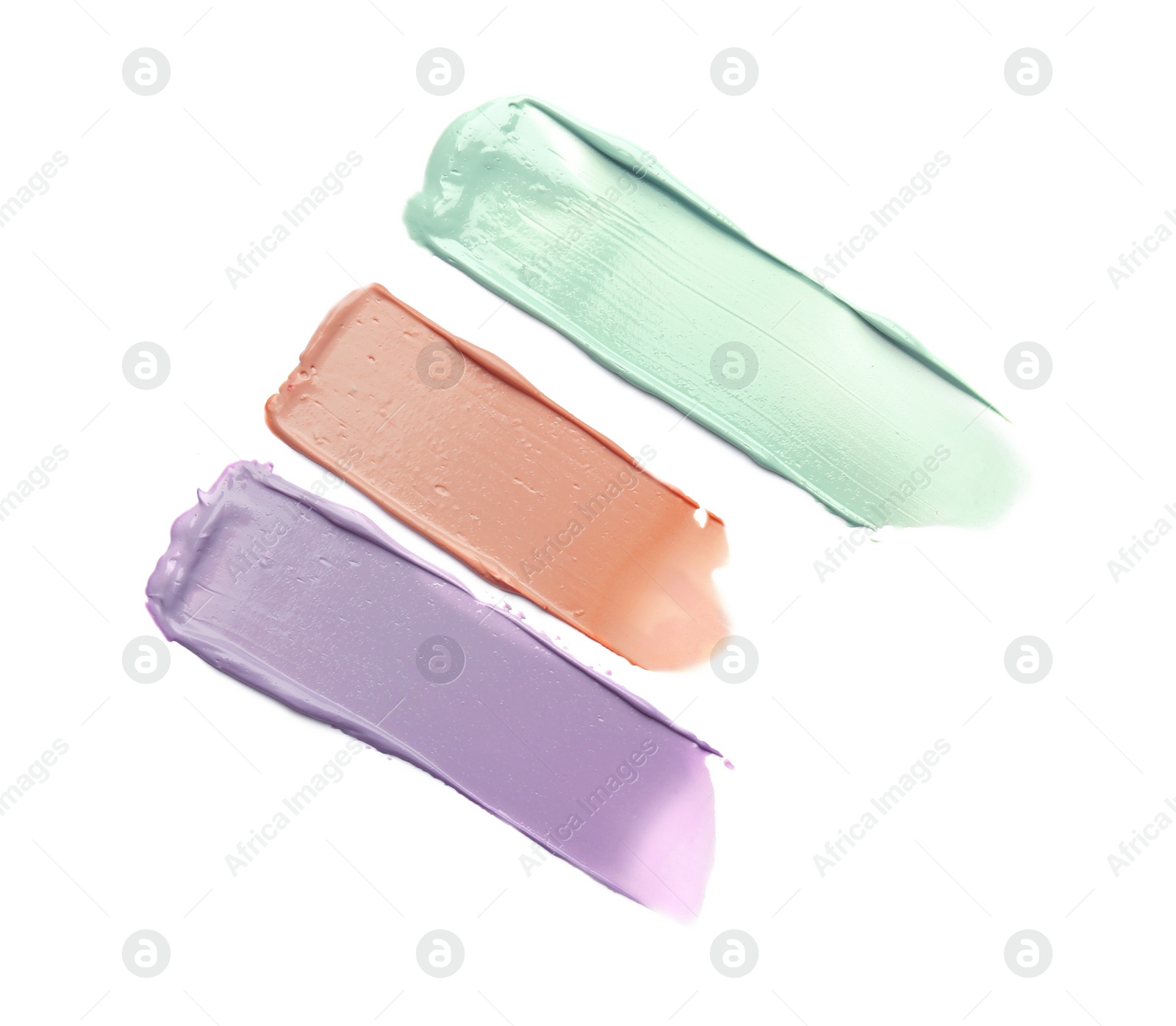 Photo of Strokes of pink, green and purple color correcting concealers on white background, top view