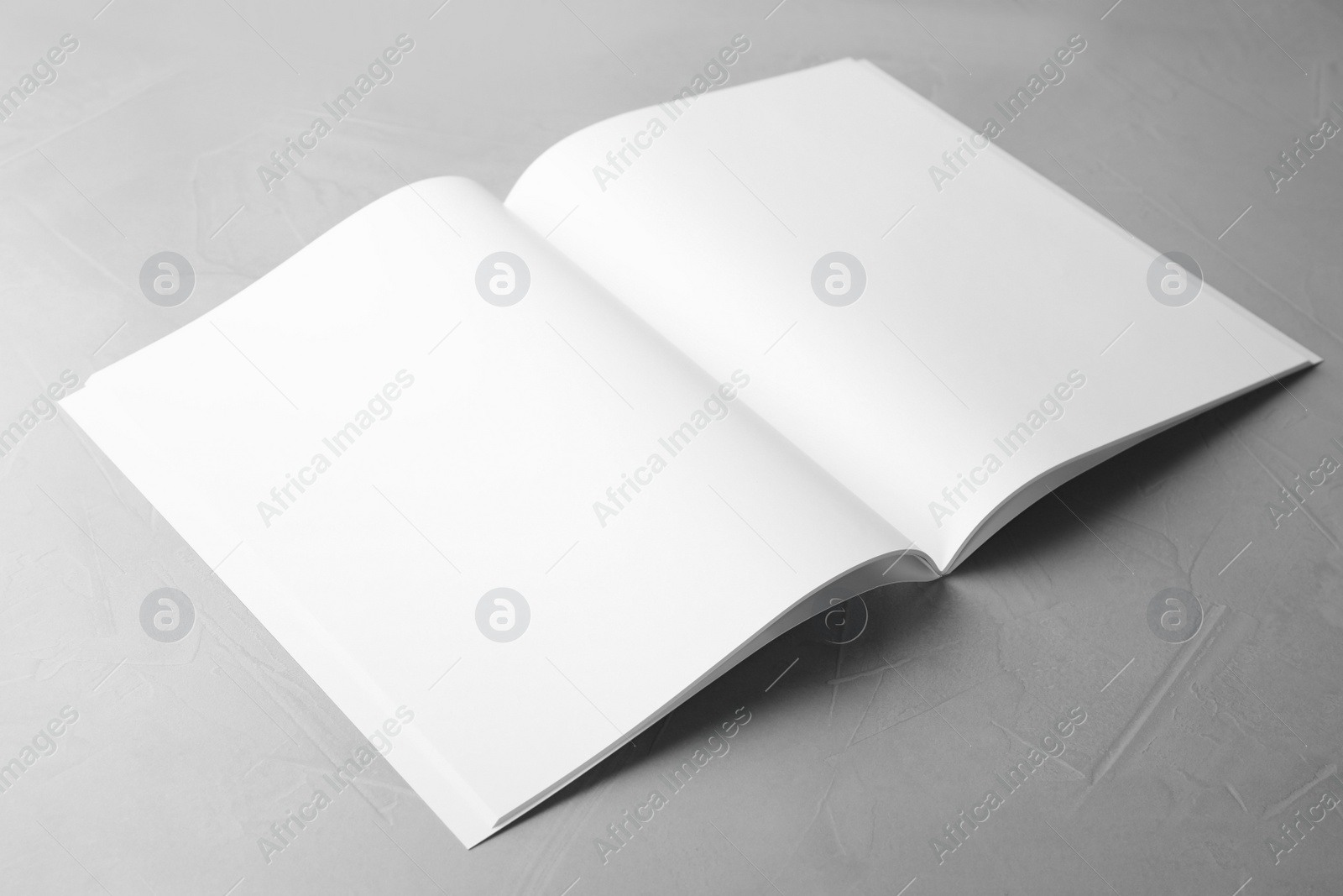 Photo of Blank open book on light grey stone background. Mock up for design