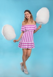 Full length portrait of pretty young woman with cotton candy on blue background