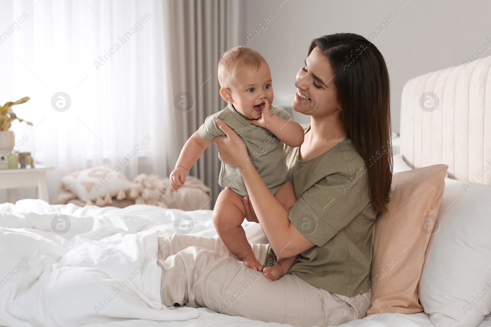 Photo of Happy young mother with her cute baby on bed at home