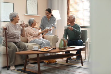 Photo of Young woman taking care of elderly people in living room