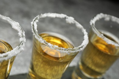 Photo of Mexican Tequila shots with salt on grey table, closeup