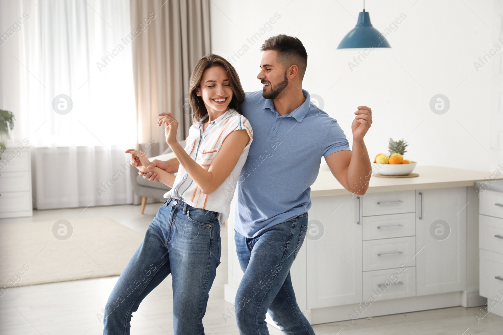 Photo of Lovely young couple dancing in kitchen at home