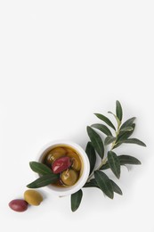 Photo of Bowl with different ripe olives and leaves on white background, flat lay. Space for text