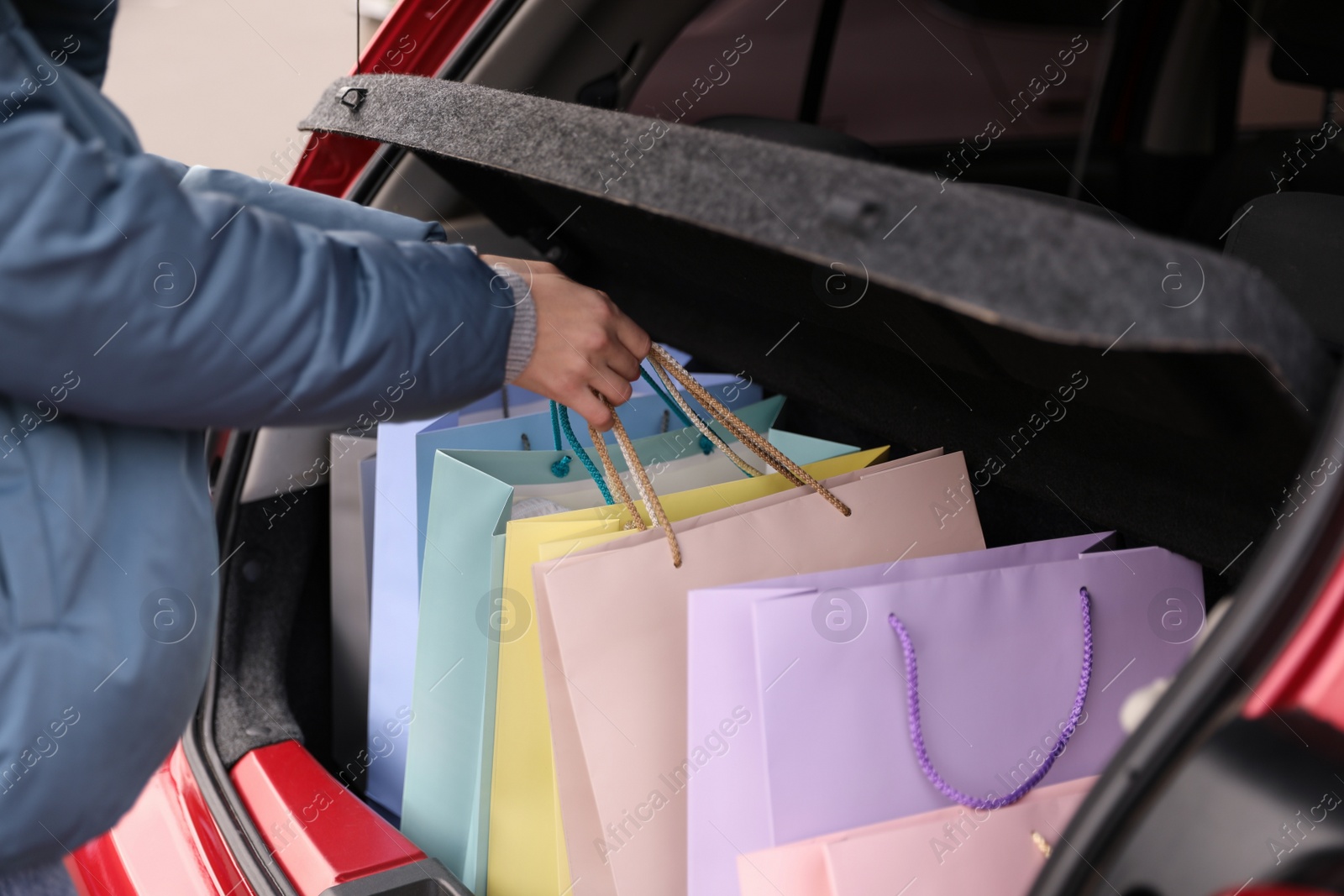 Photo of Woman putting shopping bags in car outdoors, closeup