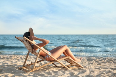 Photo of Young woman relaxing in deck chair on beach