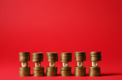 Photo of Word Export made of wooden cubes on stacked coins against red background. Space for text