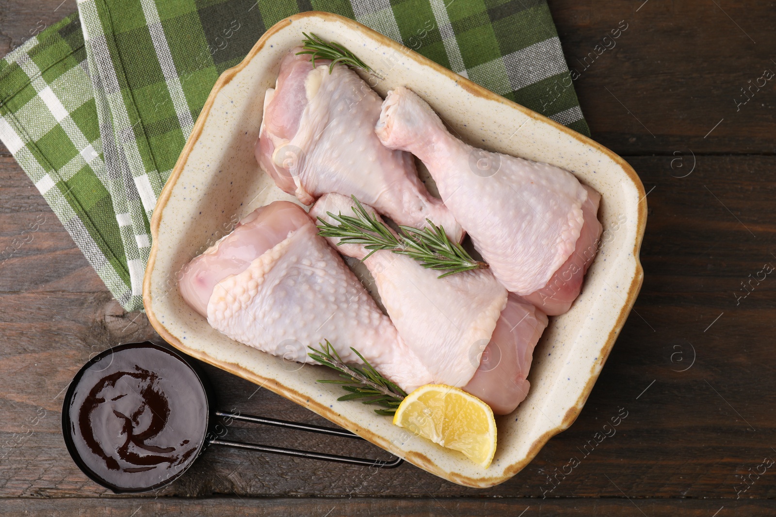 Photo of Marinade, raw chicken drumsticks, rosemary and lemon on wooden table, flat lay